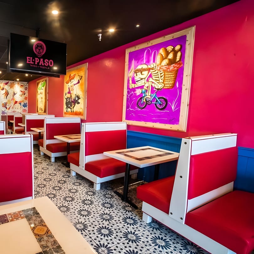 Vibrant El Paso Tacos & Tequila dining room with red booths, colorful murals, and patterned floor tiles.