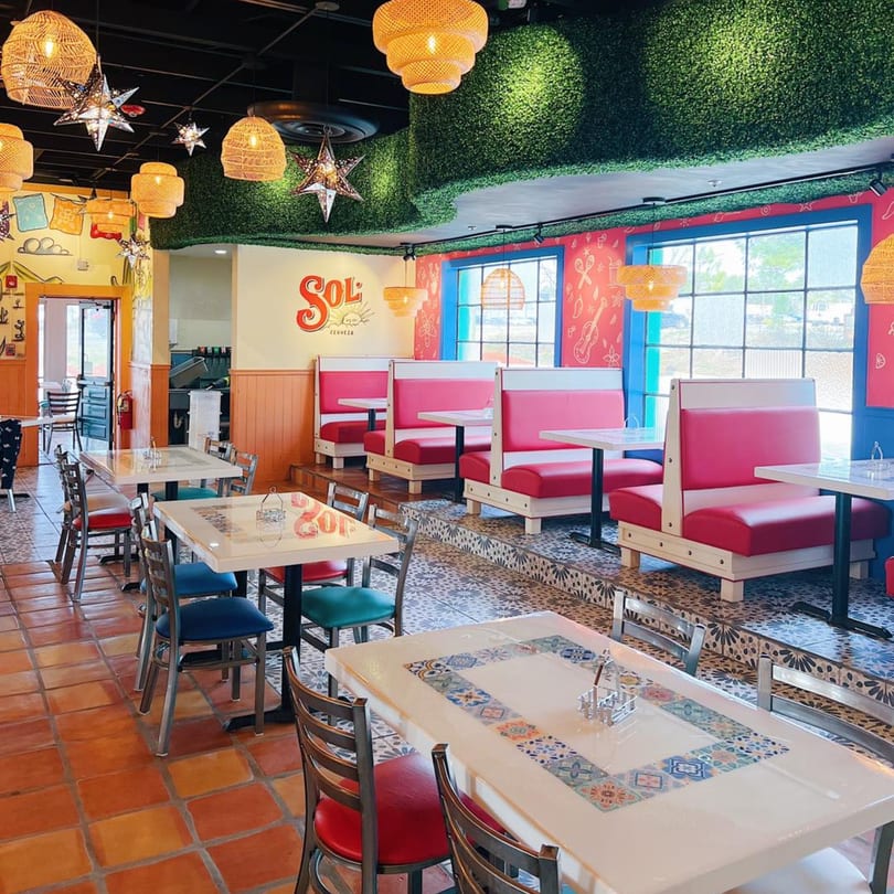 Colorful El Paso Tacos & Tequila dining room with red booths, patterned tables, and woven light fixtures.