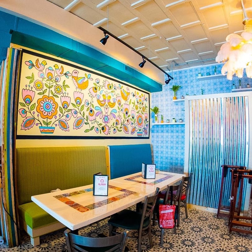 Colorful El Paso Tacos & Tequila dining room with a vibrant mural, blue tiled walls, and patterned floor.
